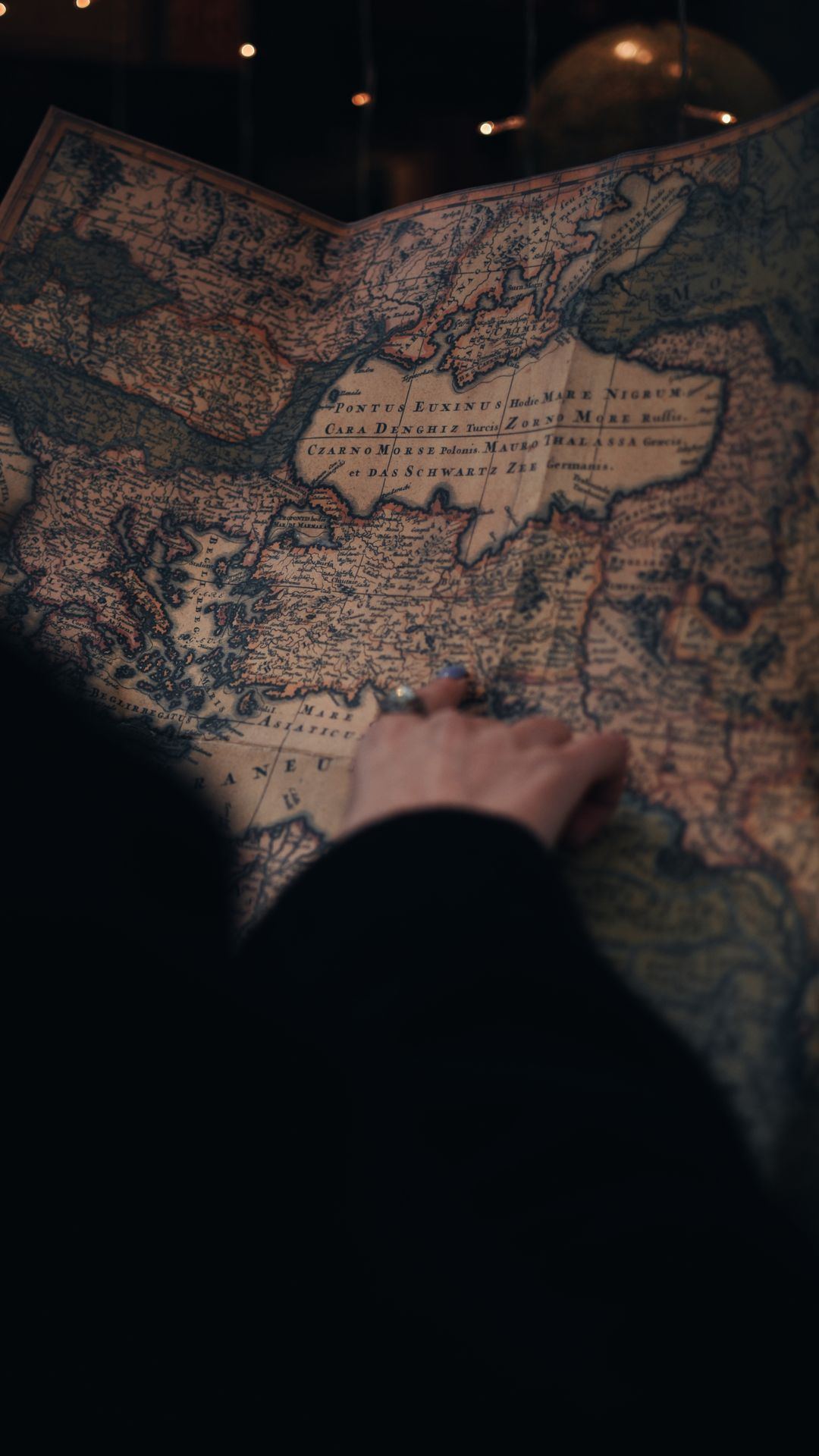 A hand tracing a route across an old map of Europe